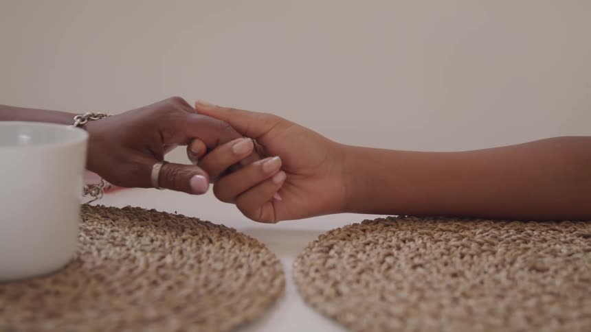 Two people are holding hands across a table