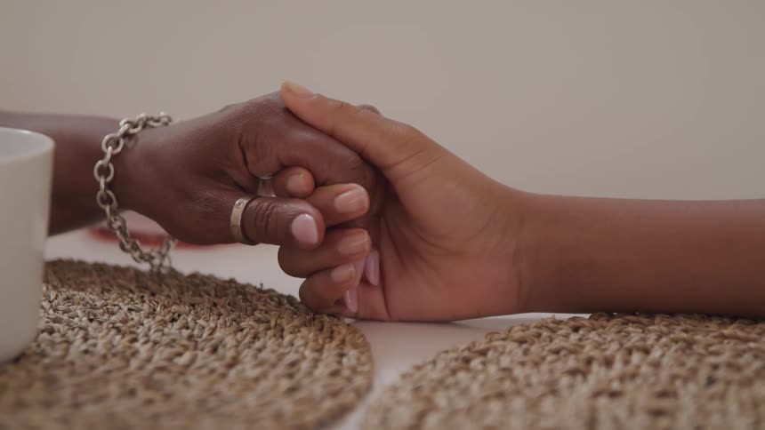 Female hands reaching across table to hold in comfort