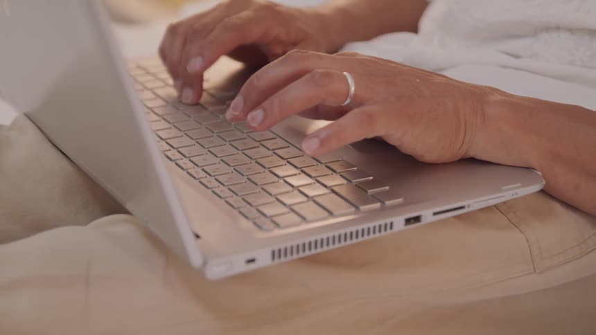 A man sits on a couch typing on a laptop
