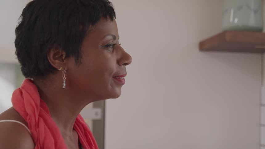 A woman slowly lifts her head and opens her eyes while sitting in a living room