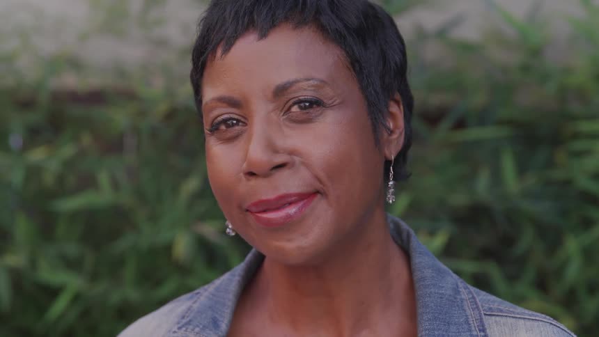 A woman smiles into the camera while standing outside