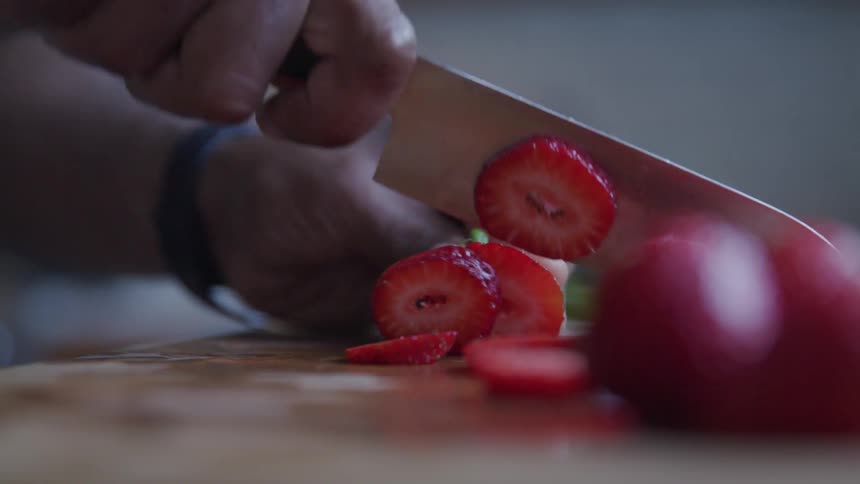 A person slices a strawberry