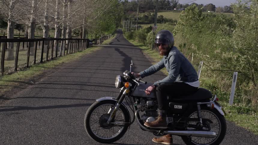 A bearded man sitting on a bike on a road