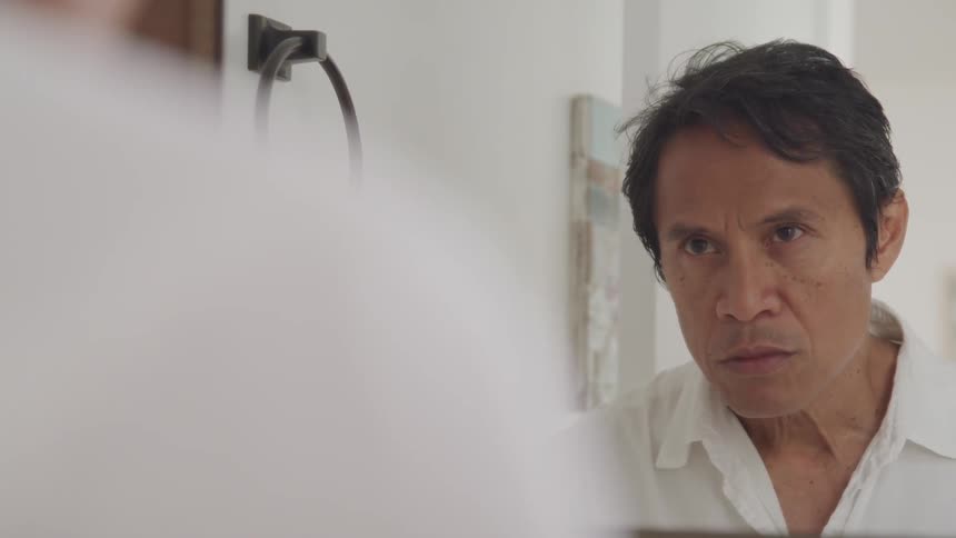 Sad man looking up and staring at the mirror