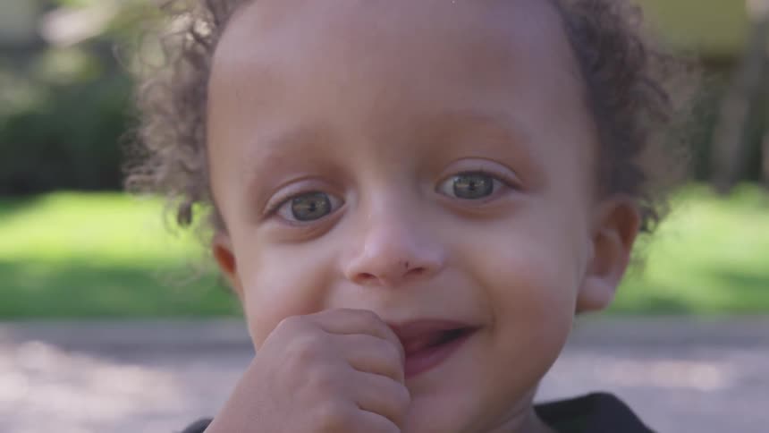 A child is smiling with his hand to his mouth