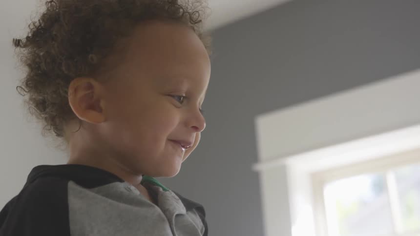 Close up of a happy baby laughing and pointing indoors