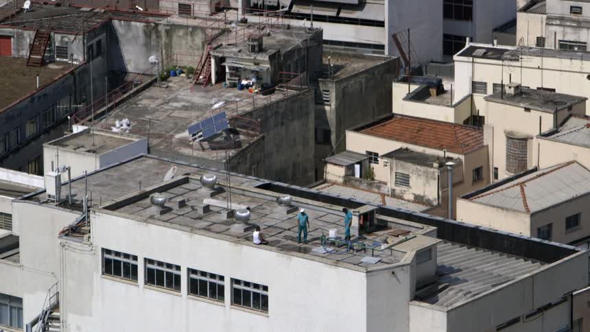Two men in blue shirts talking on the roof of a building