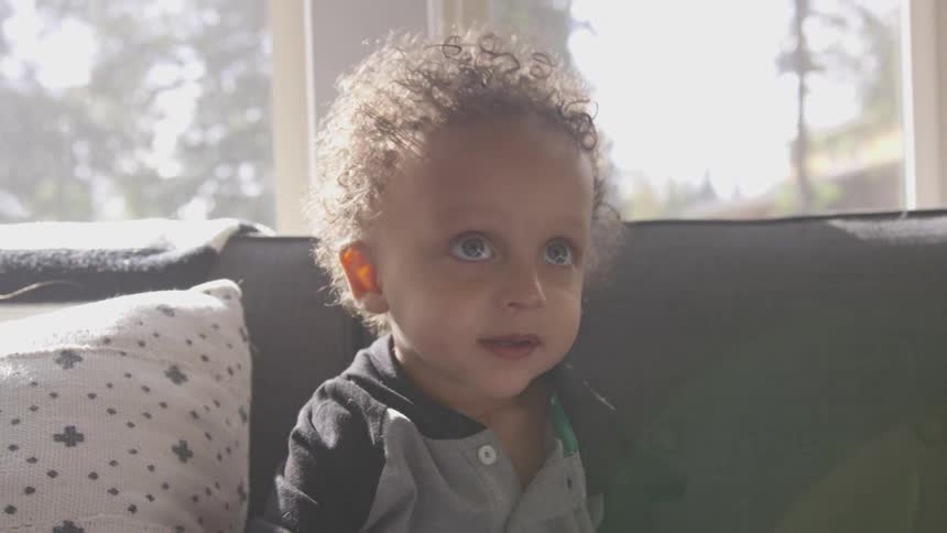 Toddler boy sits on sofa in the living room