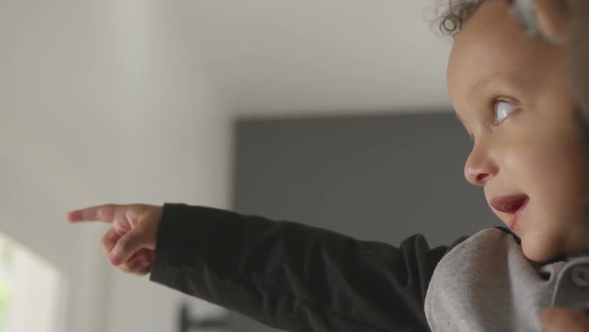 Person holds smiling pointing child