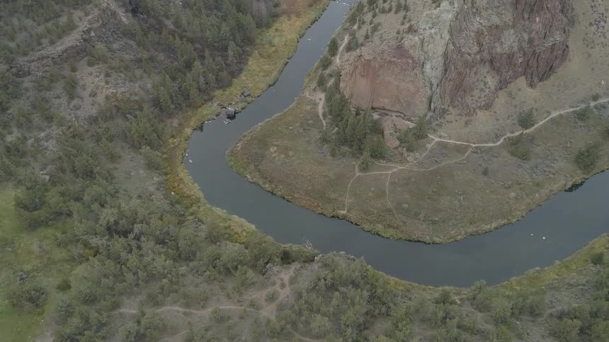 River winds between mountain and forest covered shore