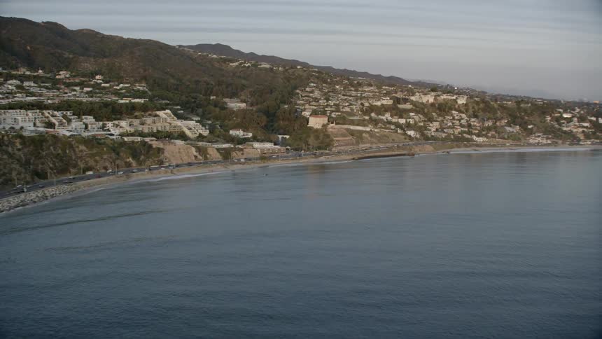A coastal neighborhood sits above a road that runs alongside the water