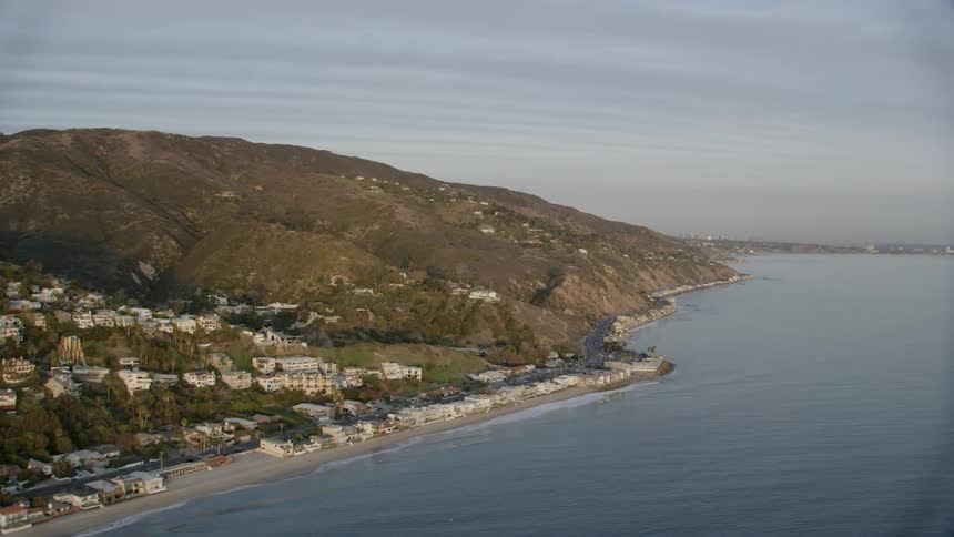 Waves lap the beach of a hilly shoreline