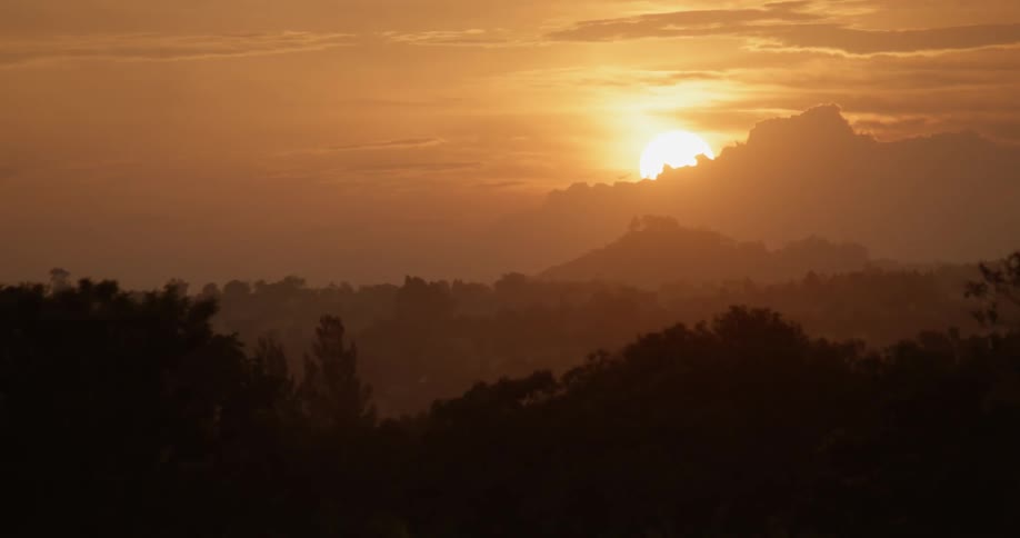The sun is nearly set behind the mountain