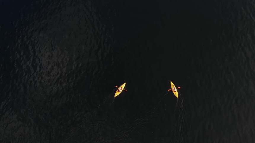 Aerial of two yellow kayaks paddling in the ocean