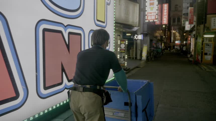 A worker is pushing a basket past buildings in the city