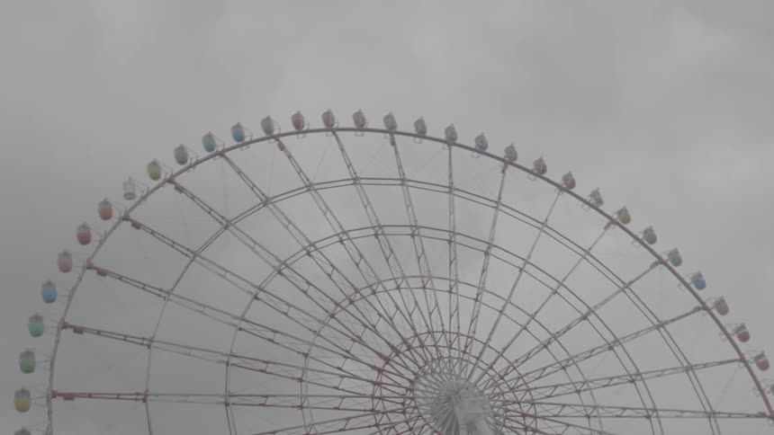 A large ferris wheel spinning on a cloudy day