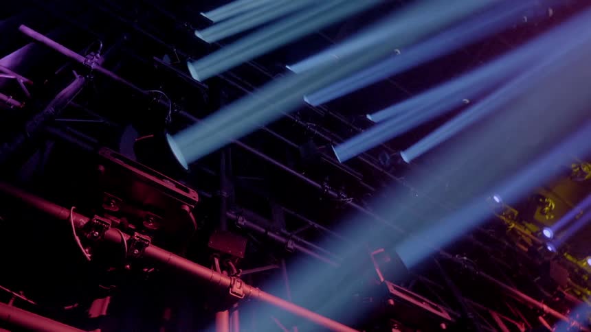 Rows of spotlights shine from a tall metal scaffolding