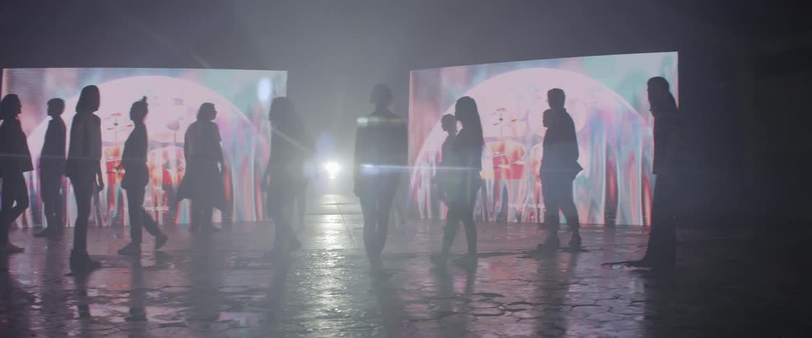 Images and 2020 are projected on screens as people turn and walk away