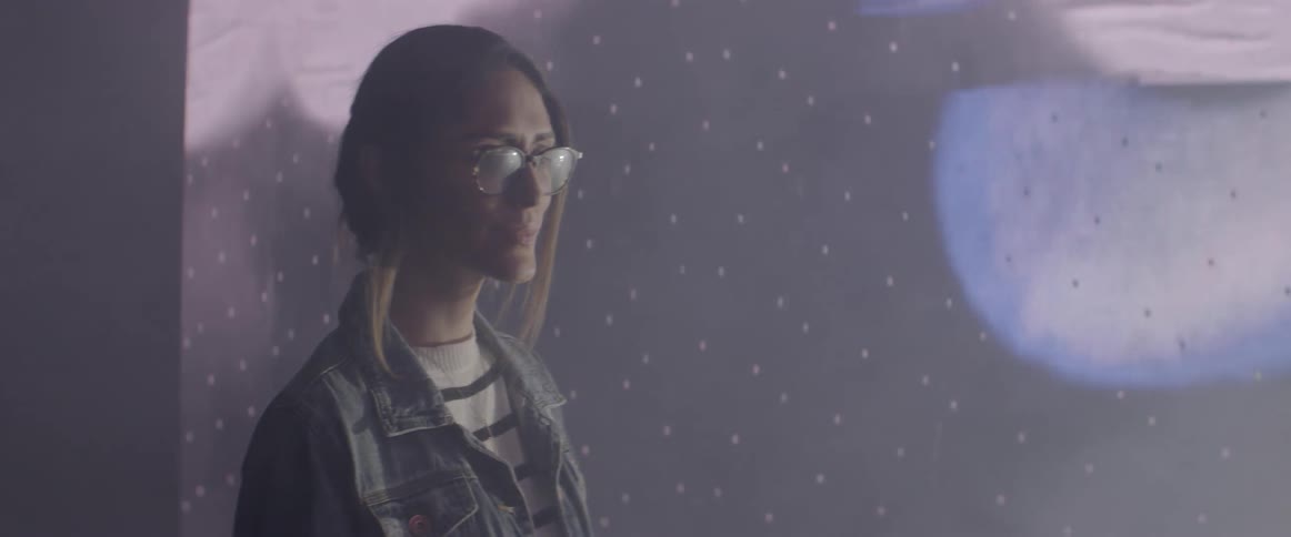 A woman with glasses in front of a screen