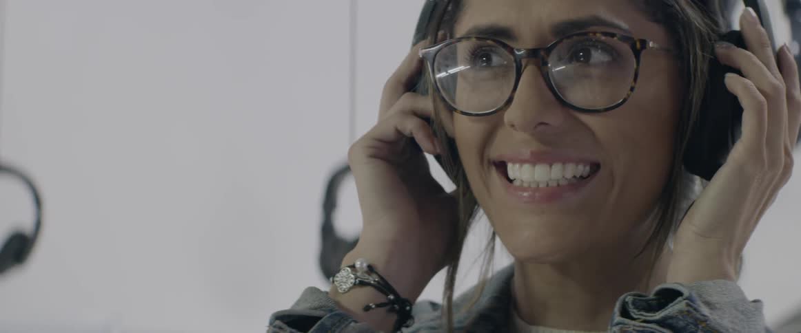 A woman puts on headphones and smiles big