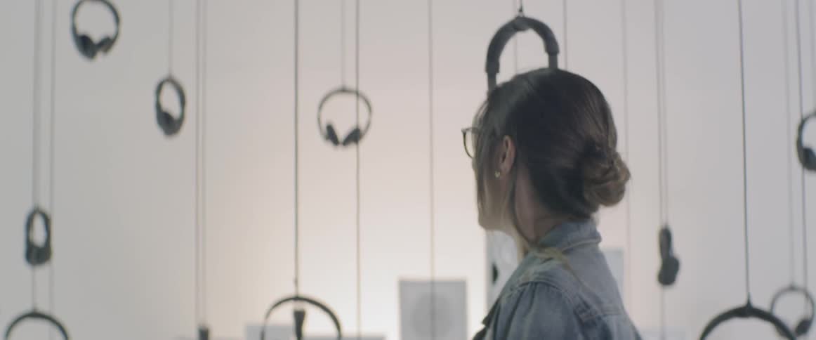 A woman looking at the headphone art installation on the gallery