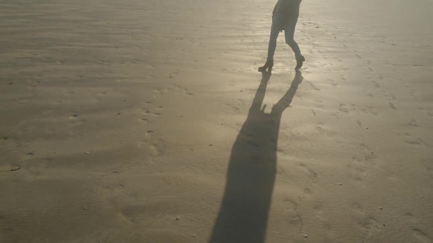 A woman walking on a beach in heels