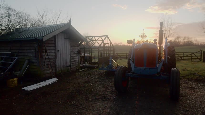 A tractor and shed on farmland in the evening