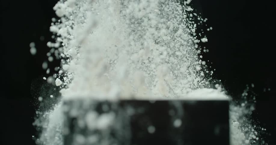 A person is picking something up from a bowl filled with powder