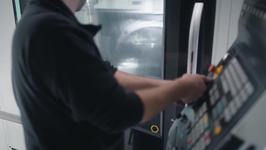A man is using the control pad for a cnc machine