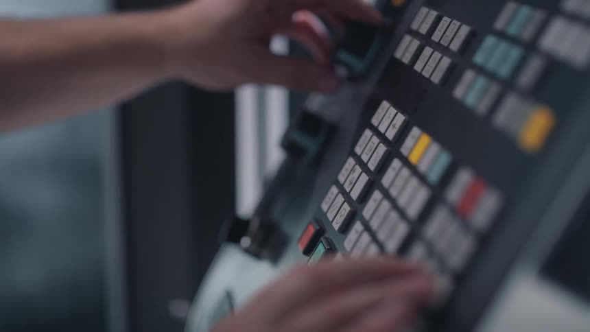 A man turns on a knob on a large control panel