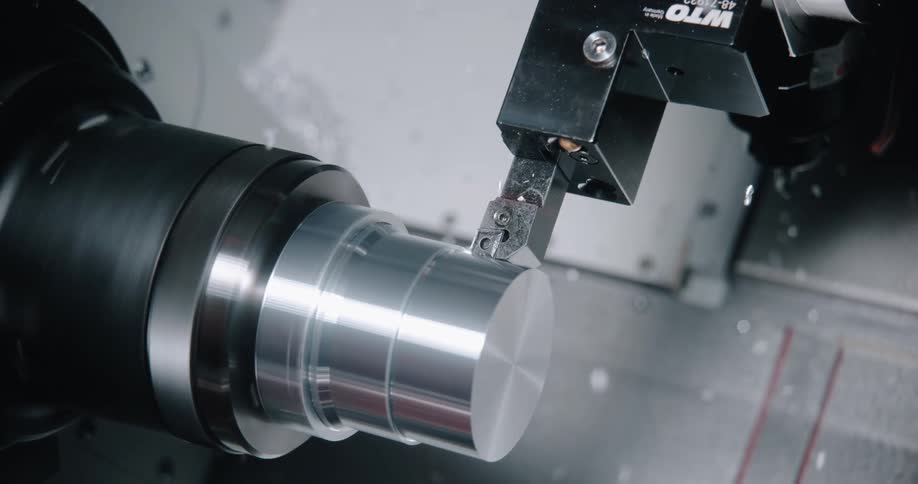 A lathe cuts into a metallic object while metal shavings fly around