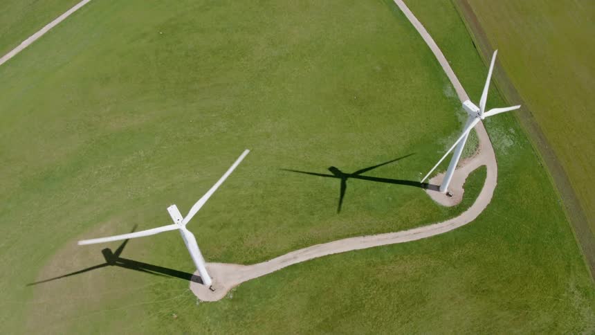 Two wind turbines are standing in a grassy field