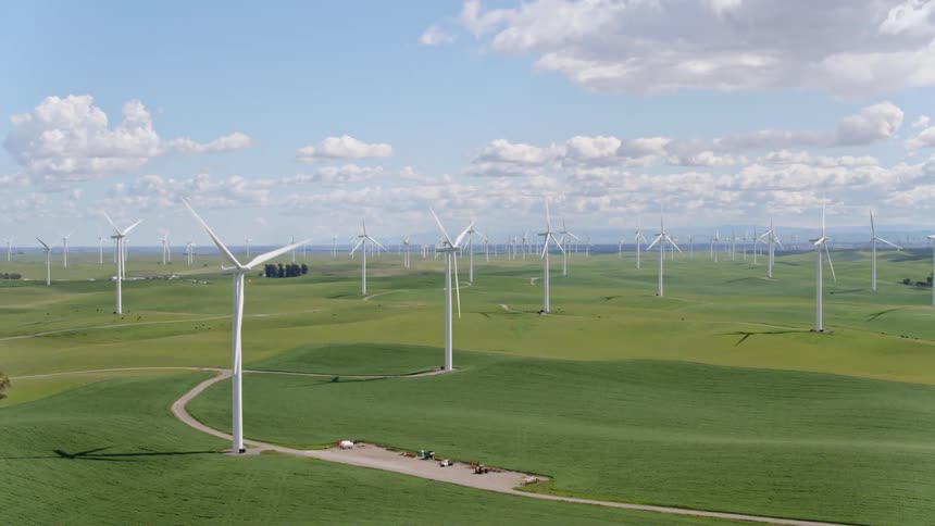 Large wind turbines spin on a coastal wind farm
