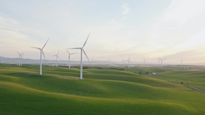 Giant windmills are spinning on a landscape of rolling hills