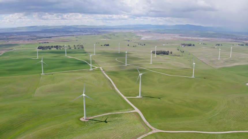 Wind turbines on a green grass field at day