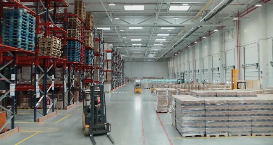 Workers drive forklifts inside a warehouse