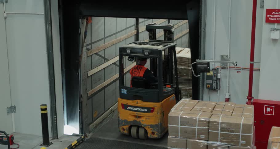 A forklift loads boxes onto a truck trailer