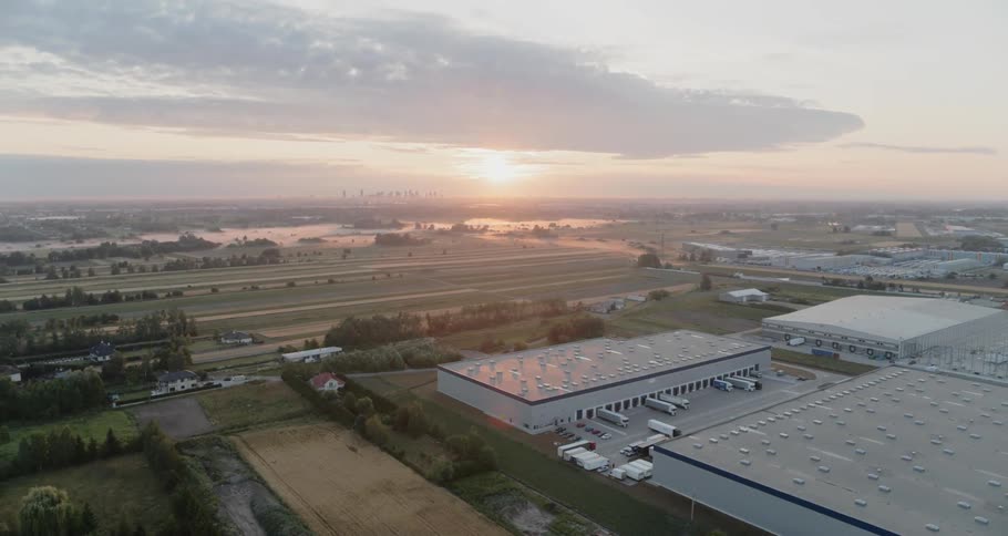 A large shipping warehouse is situated in an area with many long roads and open fields