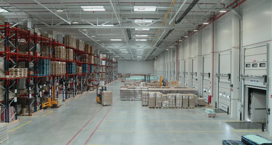 A person drives a forklift backward in a warehouse