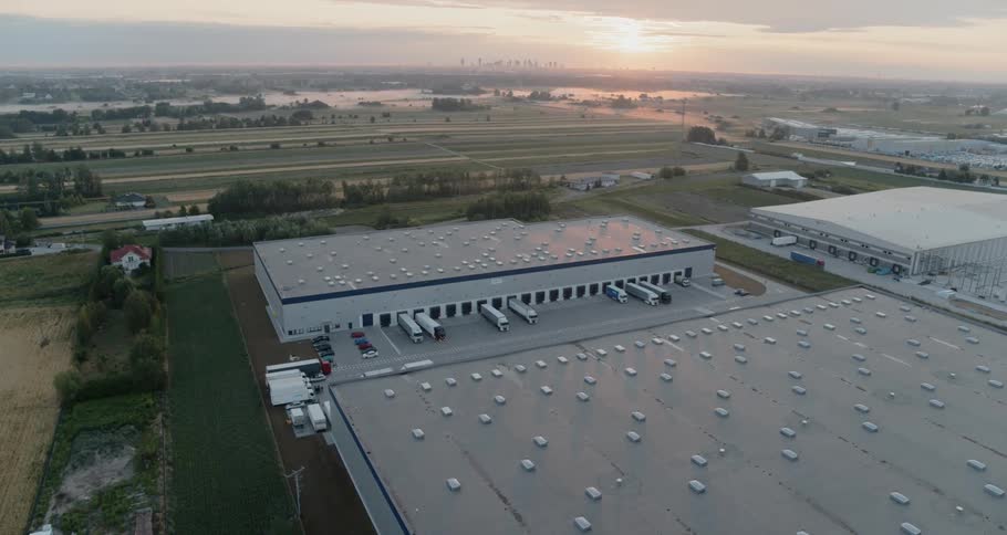 The roof tops of several warehouse buildings with semi trucks pulled up to loading doors