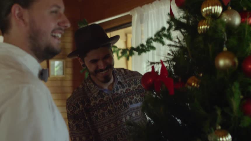 Two men talking and laughing in  front of a christmas tree