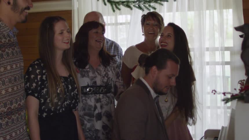 A family singing in front of a christmas tree