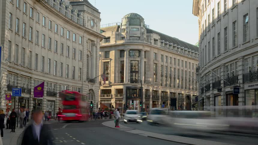 A busy street in a european city is filled with vehicles and countless pedestrians