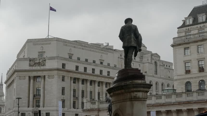 A statue of a man with buildings in the background