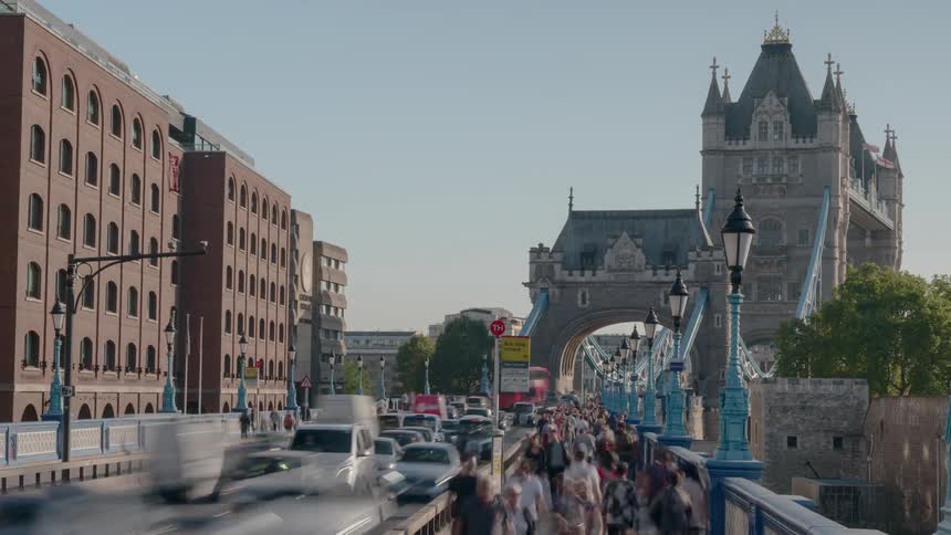 A bridge with people and vehicles with buildings and the sky in the background