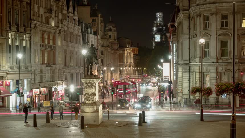 Vehicles travel a city intersection at night
