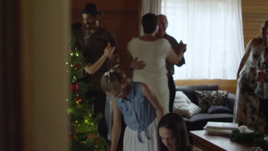 A family dancing in front of a christmas tree