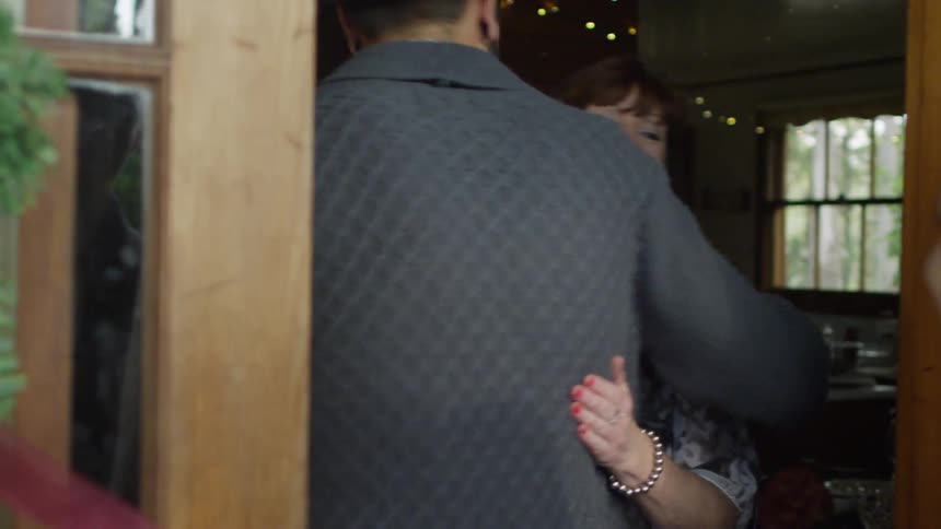 A woman greeting people at the door and hugging them