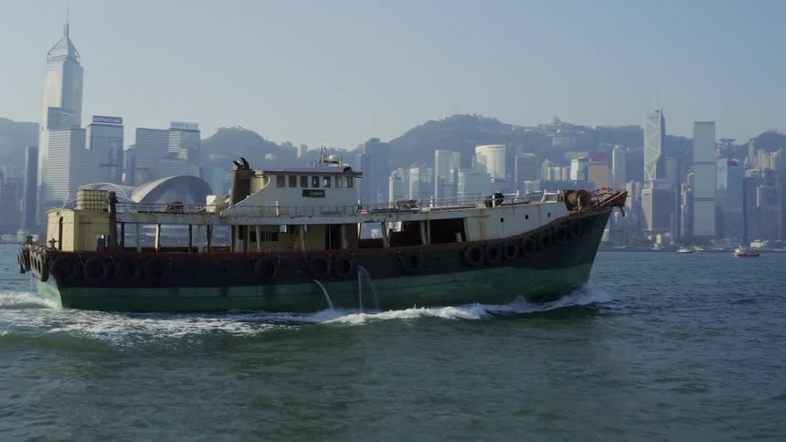 A ship motors across water near a large city