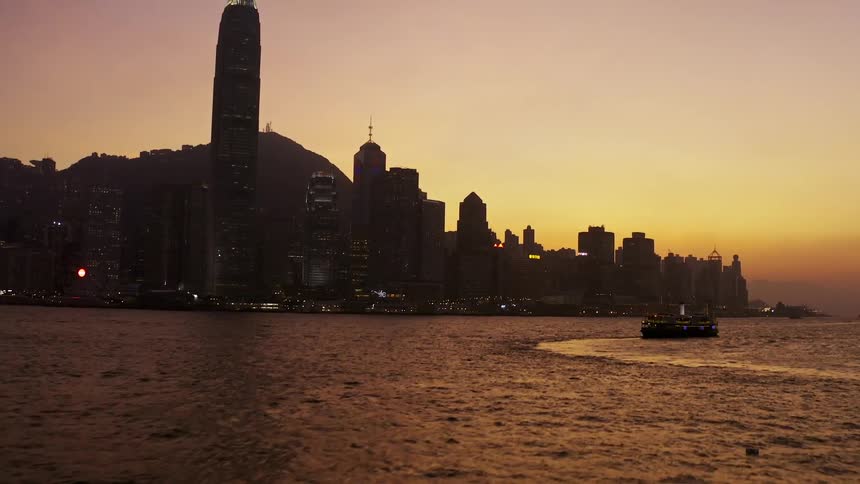 The silhouette of a major metropolitan area that is positioned next to the ocean is back lit by a setting sun